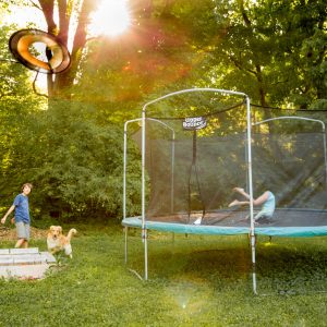 two children playing on a trampoline in a yard